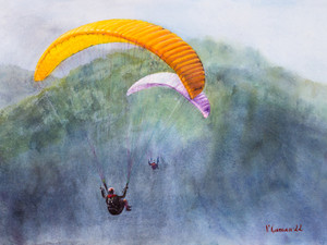 Two Paragliders hover over the mountains in a foggy haze.