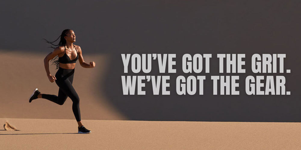 You've got the grit. We've got the gear. Photo of woman running on sand in black workout attire.