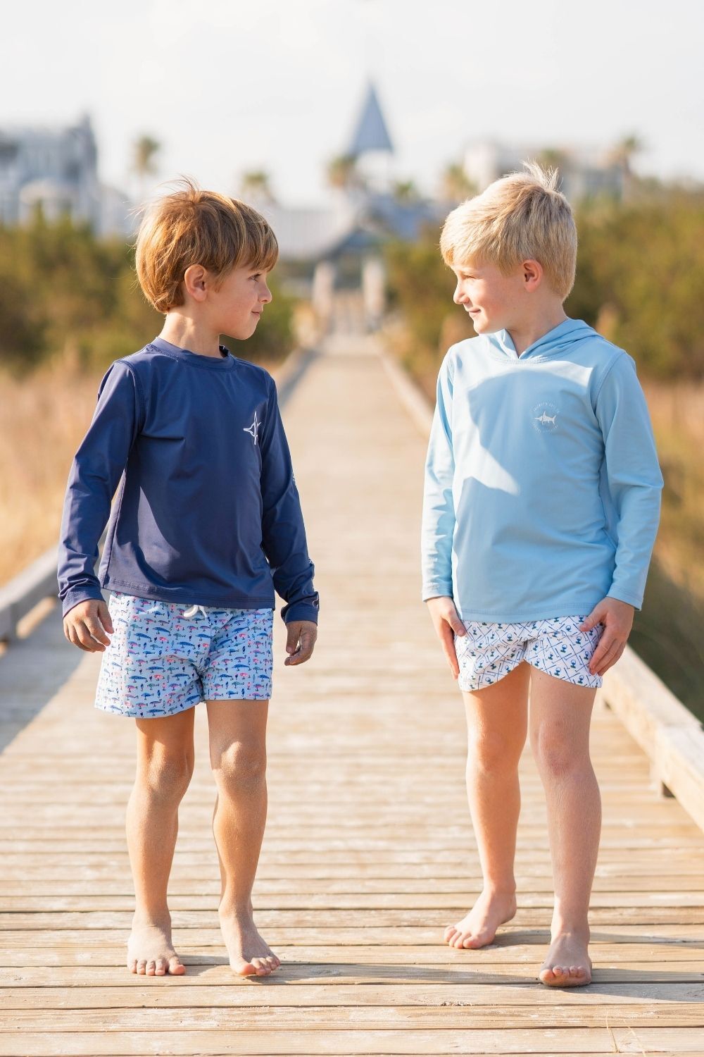 Two boys walking down a pier looking at each other while wearing Saltwater Boys apparel