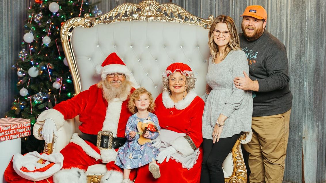 Emily and Zac with Santa and Mrs. Claus holding their daughter