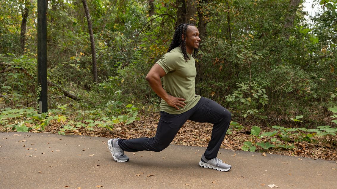 A man doing a lunge stretch while wearing On apparel and shoes