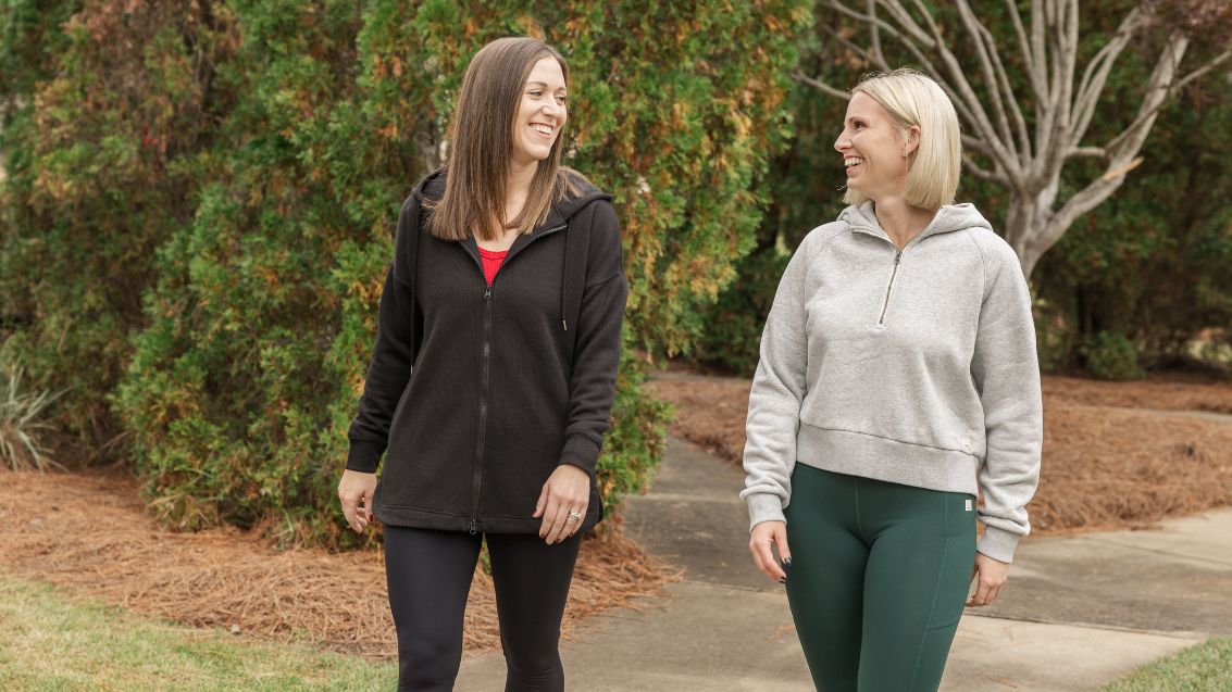 Two women walking in a park wearing Mono B and Vuori athleisure apparel.