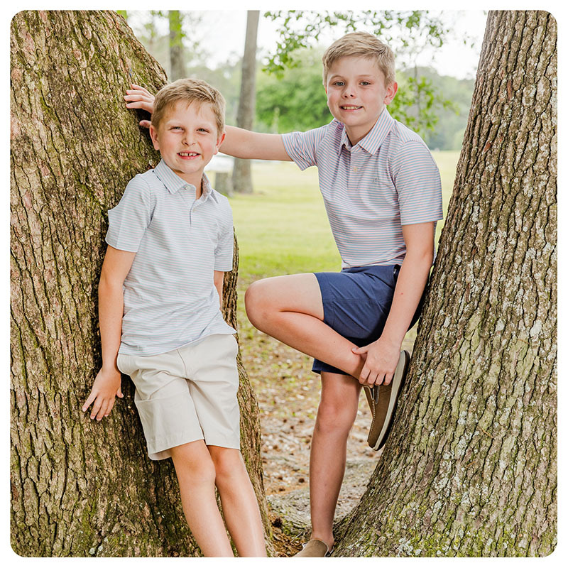 Two boys in between trees wearing new spring southern preppy apparel