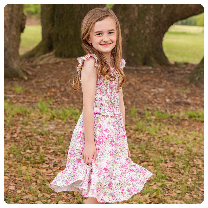 A young girl wearing a floral dress with ruffle sleeves