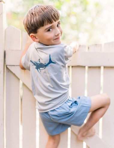 A boy, wearing Properly Tied clothing, climbing a fence