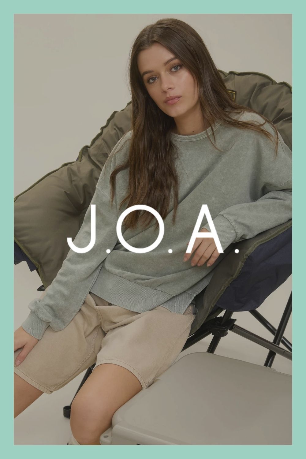 Woman sitting in chair with J.O.A. logo on top