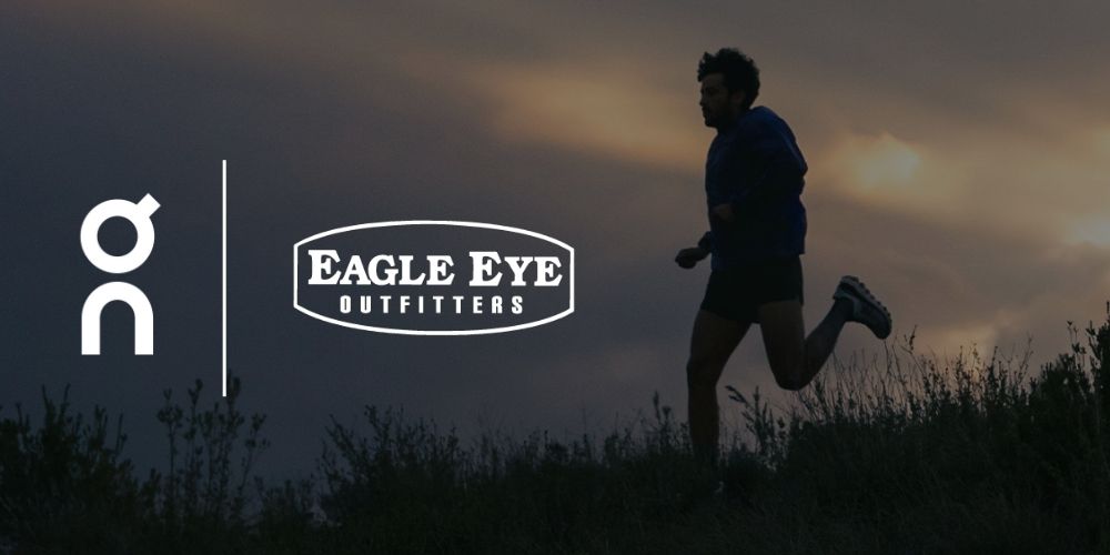 Shadow of a man running in a field at dusk wearing a pair of On Running Shoes. On and Eagle Eye Outfitters logos.