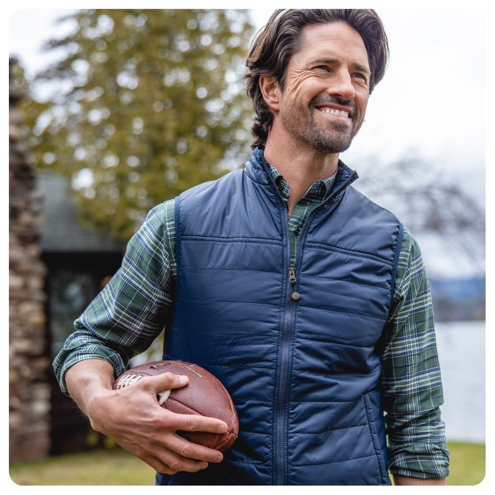 Man holding a football wearing a Duck Head vest