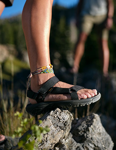 A person wearing sandals standing on a rock