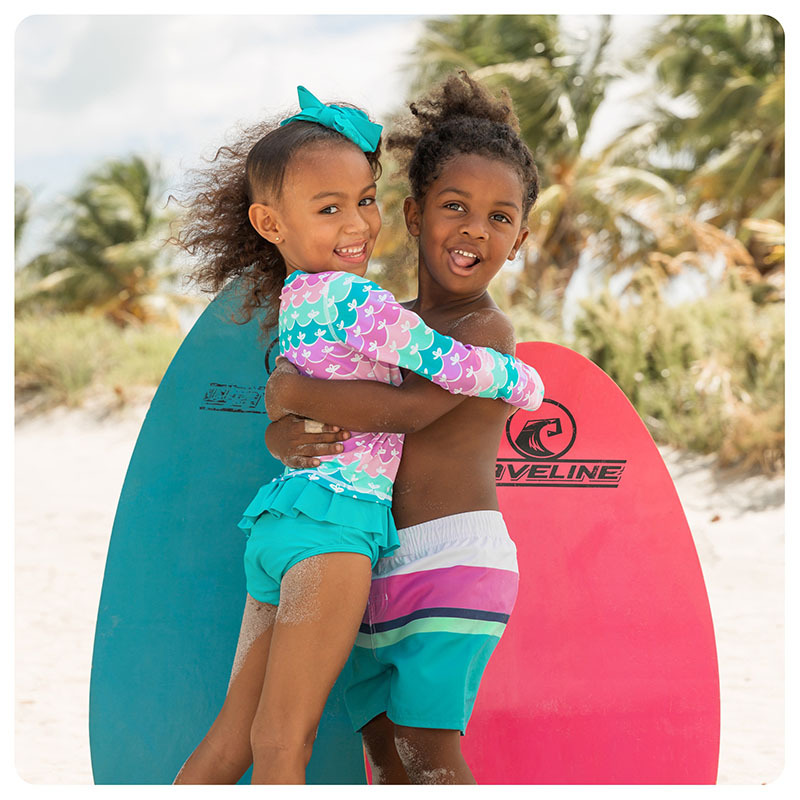 A boy and girl hugging wearing Ruffle Butts and Rugged Butts swimwear