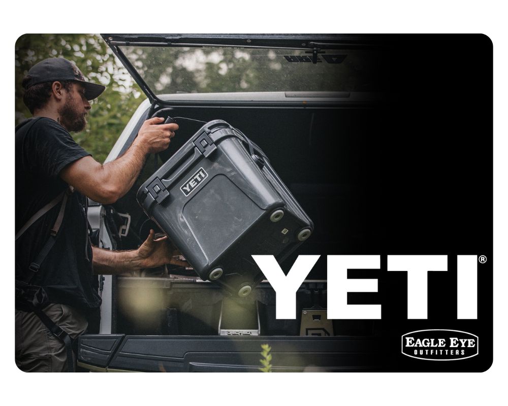 Man putting Charcoal Yeti Roadie cooler in the back of his hatchback with Yeti and Eagle Eye Outfitters logo.