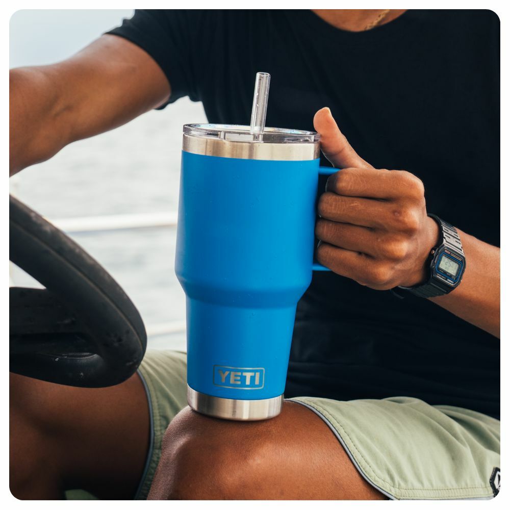 Man on a boat holding a Big Wave Blue Yeti Straw Travel Mug