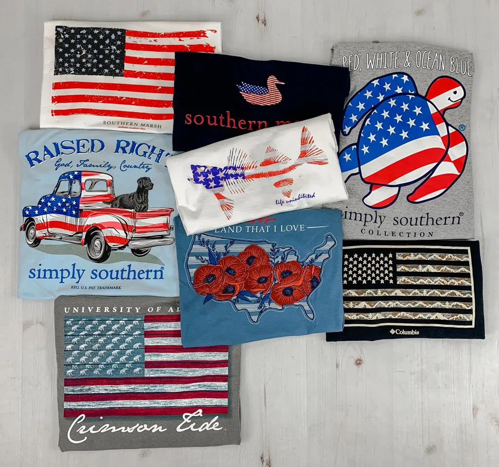 Picture of several folded t-shirts showing the back graphics with patriotic themed designs.