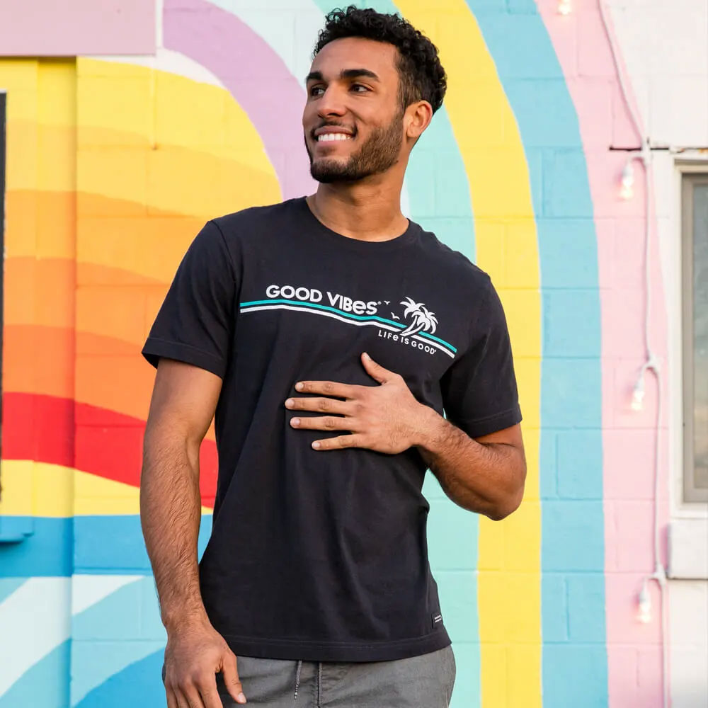 Man standing infront of a painted brick wall wearing a Navy Life is Good t-shirt.