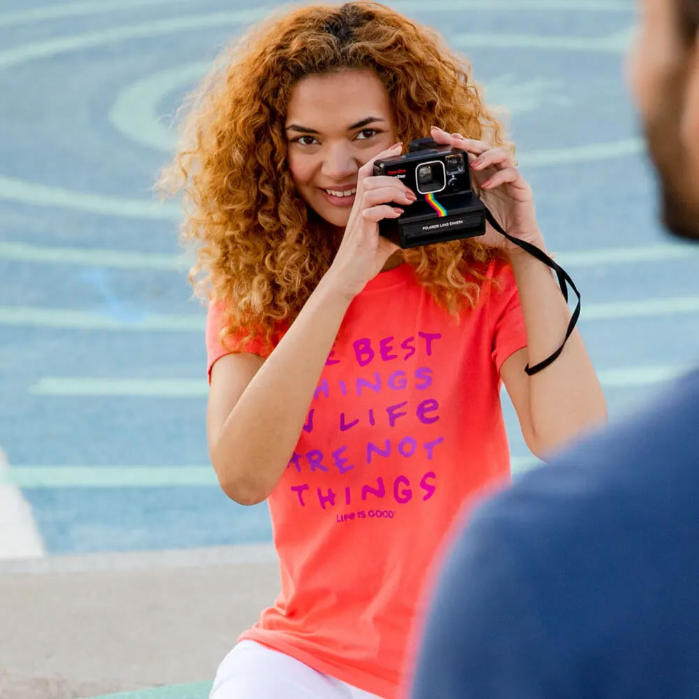 A girl about to take a photo wearing a pink Life is Good t-shirt.