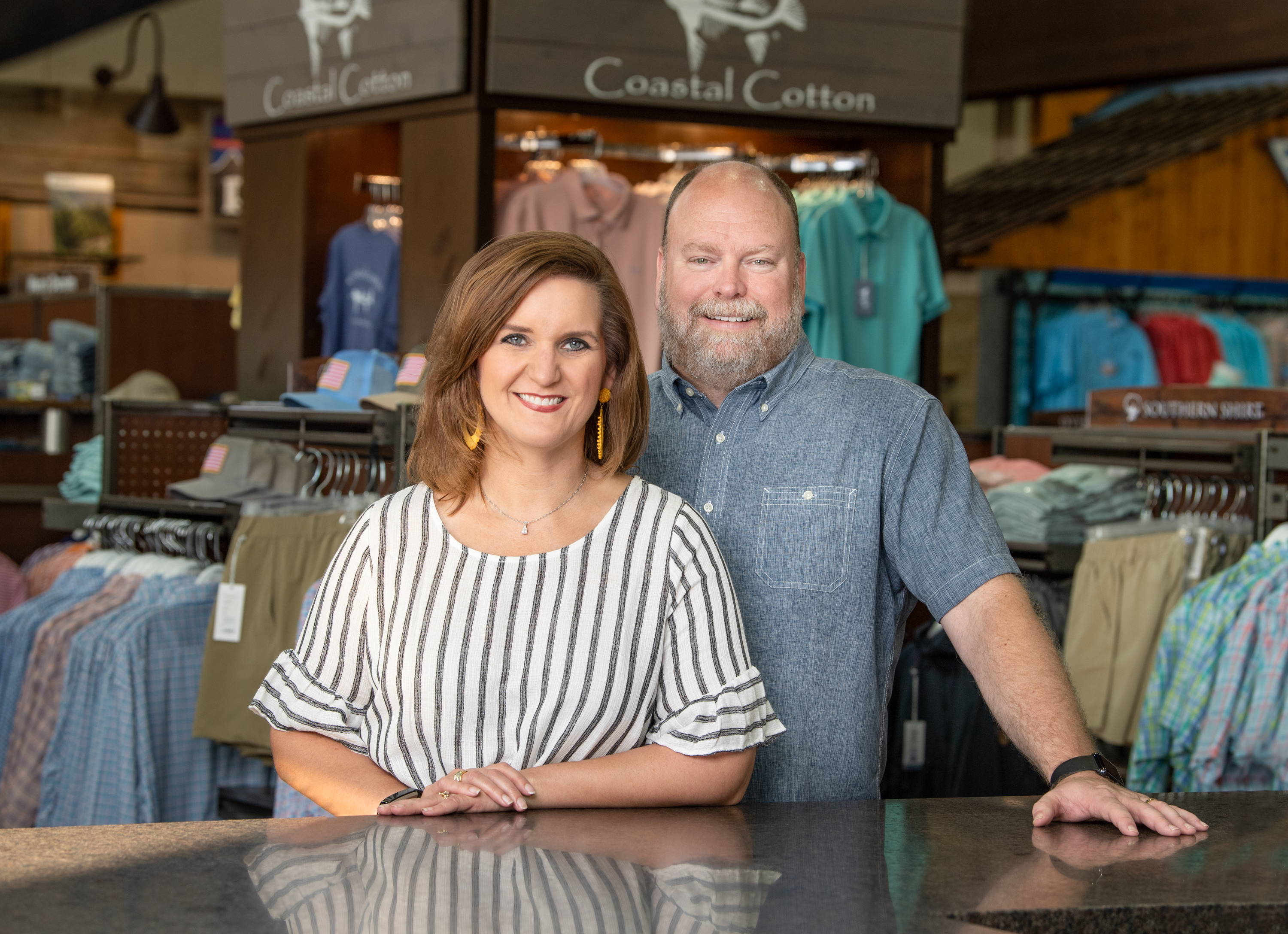 Picture of Mark and Susan Anderson at Eagle Eye Outfitters in front of Coastal Cotton apparel.