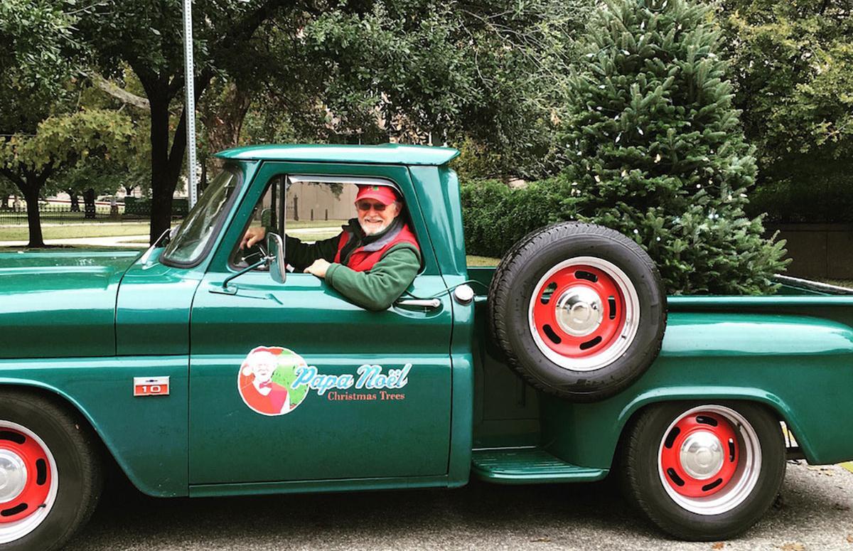 A Papa Noel staff member drives a green truck with a Christmas tree in the back, ready for holiday deliveries.
