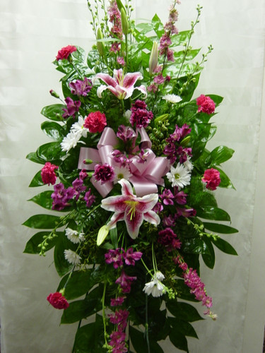 Pink Perfection Stargazer Flowers Standing Spray by Enchanted Florist TX. Flowers included are fragrant stargazer lilies, pink larkspur, hot pink carnations, purple carnations, and white daisies. Pink funeral flowers delivery in Houston TX and surrounding areas. RM522
