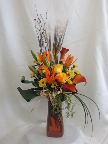 Autumn Excellence Yellow Rose Flower Bouquet by Enchanted Florist Pasadena TX. A beautiful fall bouquet of flowers and includes orange lilies, yellow roses, orange mini calla lilies, and yellow Vikings accented with branches, wheat, leaves and grasses. The bouquet comes expertly designed in a orange vase with a raffia bow.  RM235