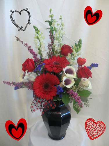 Spellbound Red & Black Valentines Bouquet by Enchanted Florist Pasadena TX. A traditional bouquet in a black vase with red, white, and purple flowers. Includes red roses, premium purple and white calla lilies, red gerberas, white larkspur making this stunning bouquet magical! RM929