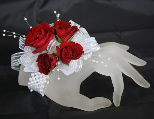 Small Iridescent Contemporary Prom Corsage by Enchanted Florist Pasadena TX. This prom corsage is on a basic pearl bracelet with red roses. PROM112