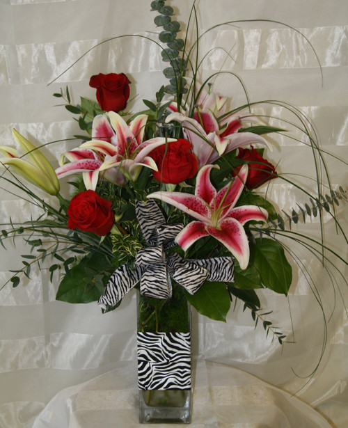 The Wild Zebra Red Roses and Stargazer Lilies Bouquet. Send flowers that will stand out. Zebra print is all the rage and this bouquet includes fragrant stargazers lilies, classic red roses, and wild for you bear grass. Approximately 27"H x 17"W.  For local delivery only.
SKU RM127