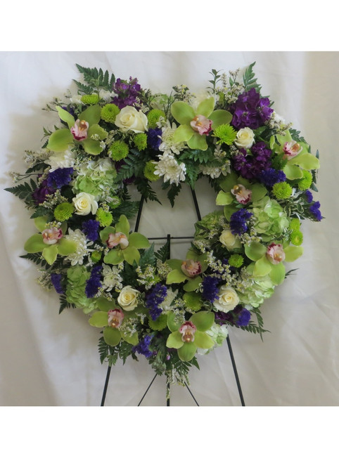 With All My Heart Shaped Funeral Wreath Flowers by Enchanted Florist Pasadena TX. Heart shaped funeral wreath of sympathy flowers including green cymbidium orchids, white roses, green hydrangeas, white cushions, and purple stock. Heart shaped funeral flowers. RM540