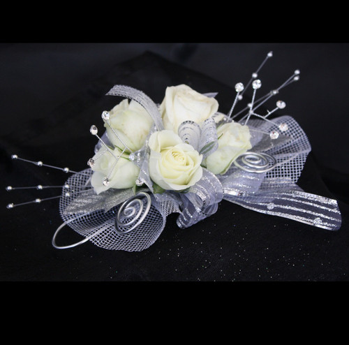 Basic All Silver Traditional Prom Corsage by Enchanted Florist Pasadena TX. This basic prom corsage is our traditional corsage design built on wire to fit every size wrist, perfect for the small sizes. Includes basic bling in silver colored trim with white roses. PROM114