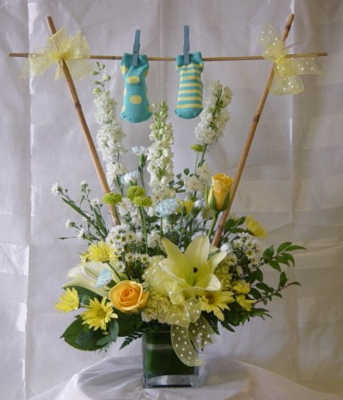 Baby Boy Clothesline Flower Bouquet with Socks by Enchanted Florist Pasadena TX. The adorable bouquet includes yellow roses, yellow oriental lilies, white larkspur, & yellow daisies in a yellow & white theme. SKU RM319
