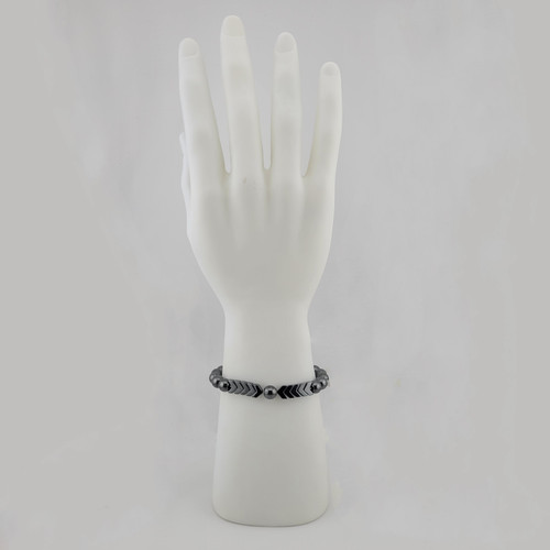 Hematite arrow and round bead bracelet displayed on white hand stand with polished metallic gray stones.