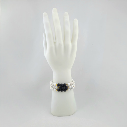 Howlite and lava stone bracelet with white marbled beads and black porous lava stones shown on hand jewelry display.