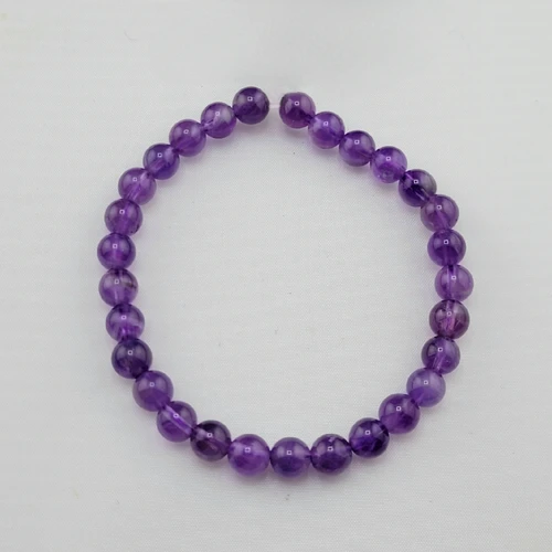 Amethyst gemstone bead stretch bracelet laid flat on a clean white surface showing the circular uniform shape.