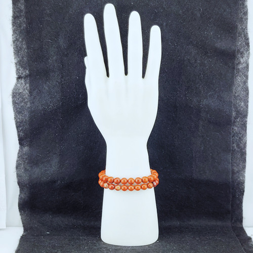 Two Red Jasper bracelets displayed on a white mannequin hand against a dark textured backdrop.