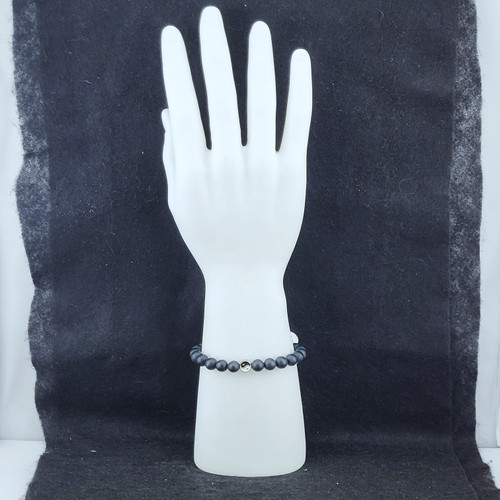 A stack of Lava Stone bracelets displayed on a white mannequin hand against a dark textured background.