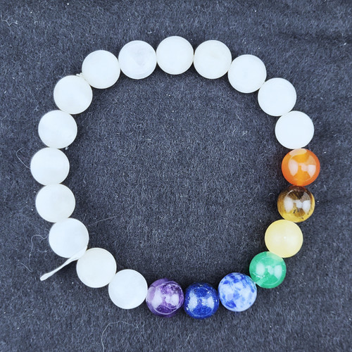 A Selenite stretch bracelet featuring white beads and seven colorful chakra gemstone beads on a clean white background.