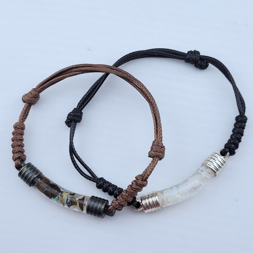 An adjustable leather bracelets featuring a glass vial center filled with floating Australian Opals in glycerin.