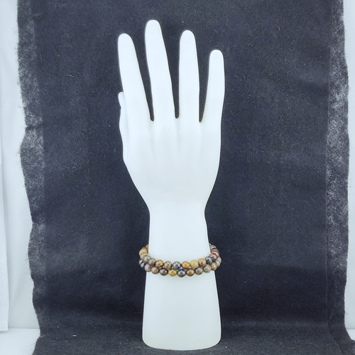 A stack of Pietersite bracelets on a white mannequin hand showing the unique variation of each natural bead.