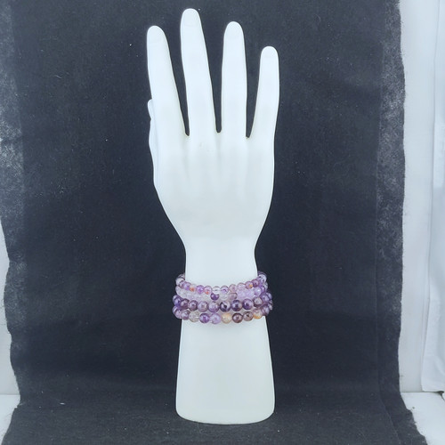 A stack of Super 7 bracelets displayed on a white mannequin hand to show the unique patterns of each bead.