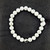 Howlite bead bracelet with yin yang charm showing white stones with gray marbling on black background.