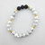 Howlite and lava stone bracelet with white marbled beads and black porous lava stones on white background.