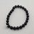 Black tourmaline 8mm bead bracelet laid flat on white background