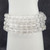 Close-up of polished Clear Quartz beads on a white mannequin arm showing high transparency.