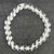 Overhead view of a 8mm natural Clear Quartz bead bracelet on a dark surface.