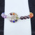Close-up view of a silver Tree of Life charm featuring small inset gemstones connected to purple and red beads.