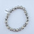 A single Dalmatian Jasper stretch bracelet featuring cream-colored beads with black spots on a white background