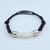 An adjustable black leather bracelet featuring a glass vial center filled with floating Australian Opals in glycerin.
