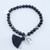 A Gold Sheen Obsidian stretch bracelet with tree of life charm and tassel on a white background.