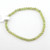 A single strand Peridot gemstone bracelet laid flat on a white surface, showcasing the vibrant olive-green natural stones.