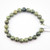 A single strand Serpentine gemstone bracelet laid flat, showcasing the high-gloss finish and organic stone textures.