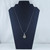 Polished Rutilated Quartz teardrop pendant featuring golden needle-like inclusions and a silver bail on a black jewelry bust.